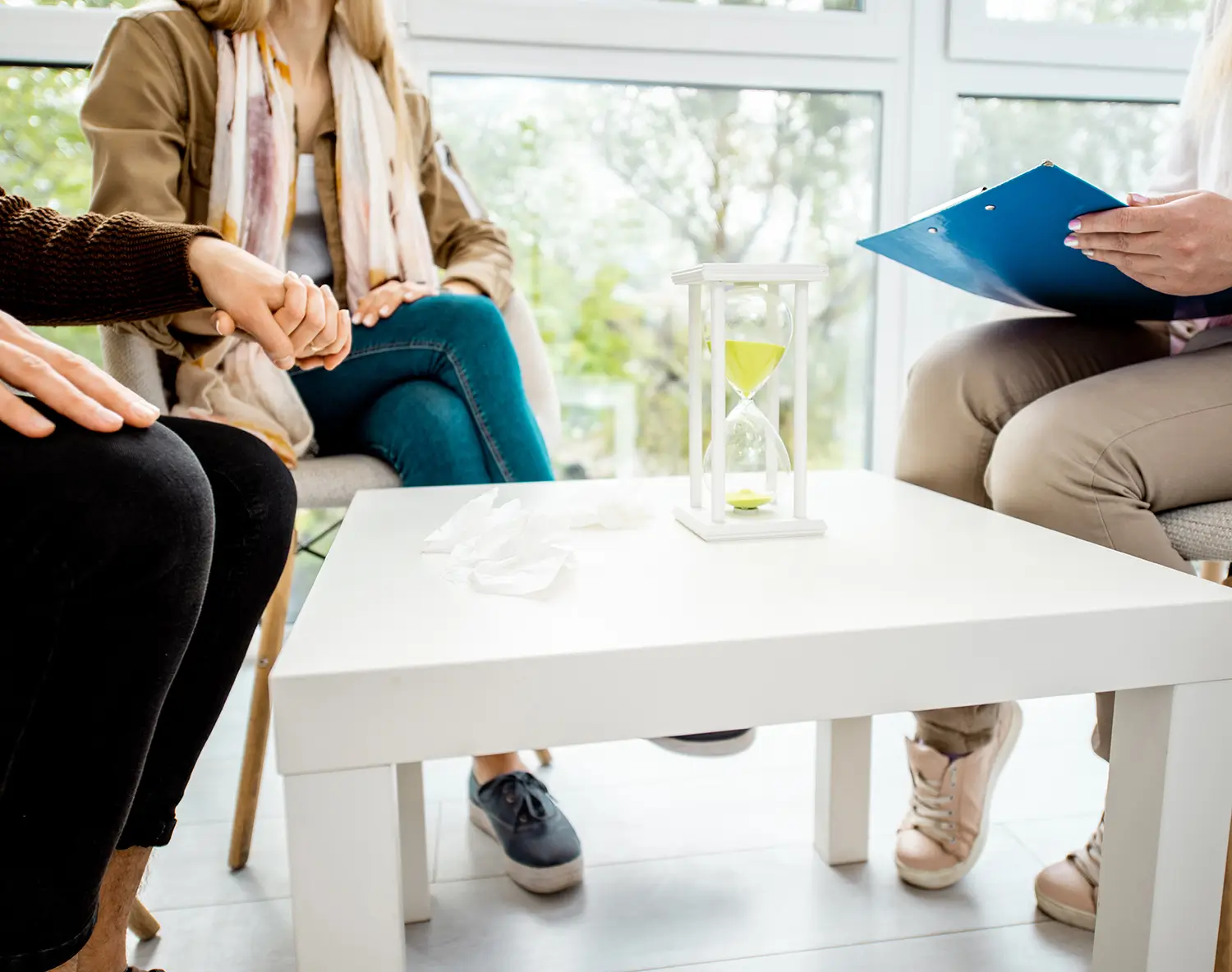 An hourglass on a table beside people talking, marking the passage of time
